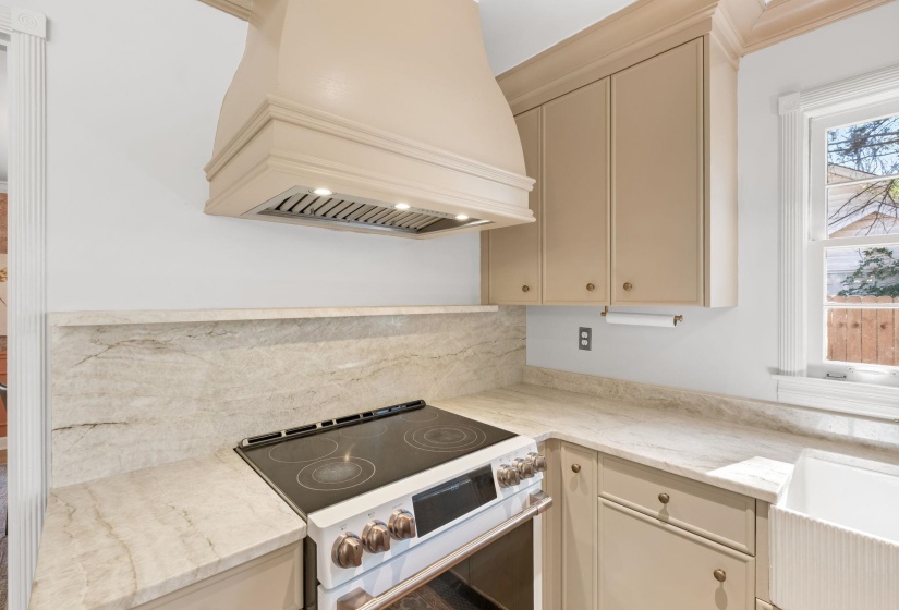 Kitchen with cream cabinets, white electric range, premium range hood, and light stone countertops