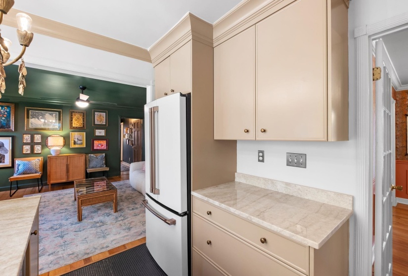 Kitchen featuring cream cabinets, ornamental molding, high end fridge, and dark wood-style floors