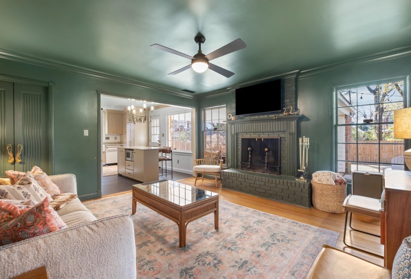 Living area featuring ornamental molding, a fireplace, light wood finished floors, a chandelier, and ceiling fan