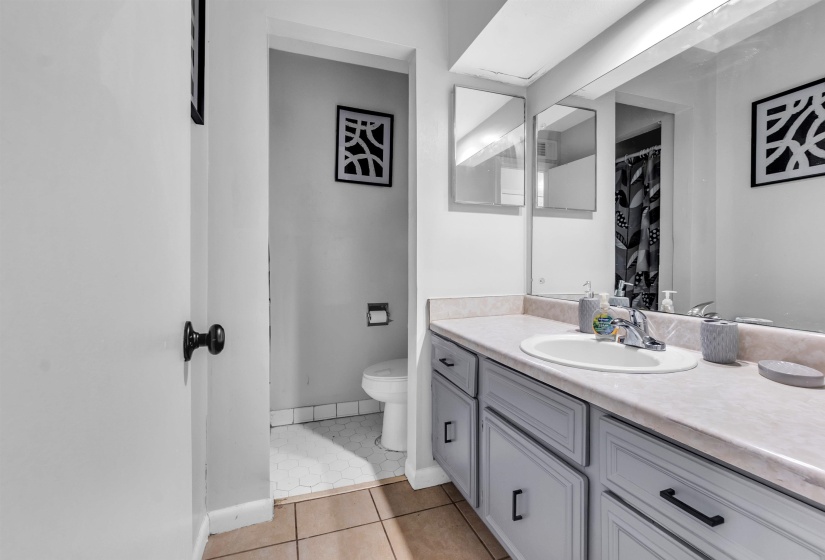 Full bathroom with curtained shower, vanity, and light tile patterned floors