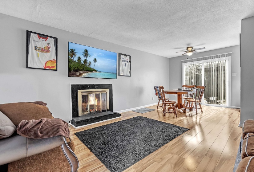 Living room with a ceiling fan, a fireplace, wood finished floors, and a textured ceiling