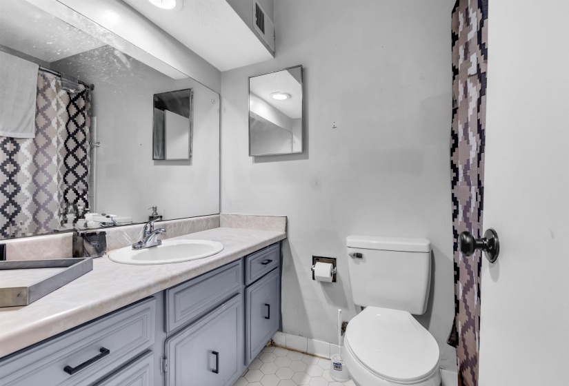 Full bath featuring a shower with shower curtain, vanity, and light tile patterned floors
