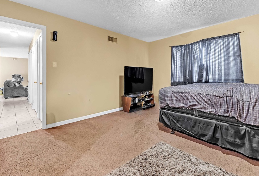 Tiled bedroom featuring carpet floors and a textured ceiling