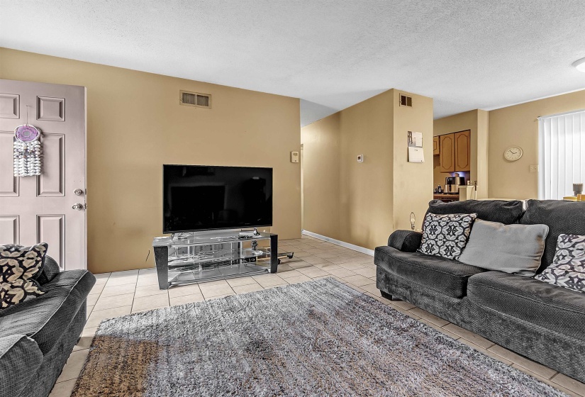 Living room with a textured ceiling and light tile patterned floors