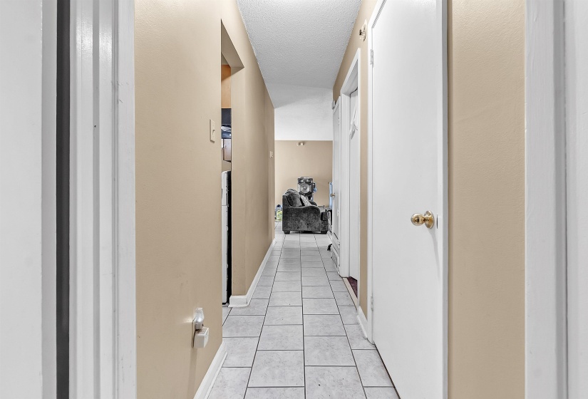 Corridor featuring light tile patterned flooring and a textured ceiling