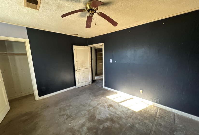 Unfurnished bedroom with a textured ceiling, a ceiling fan, a closet, and unfinished concrete floors