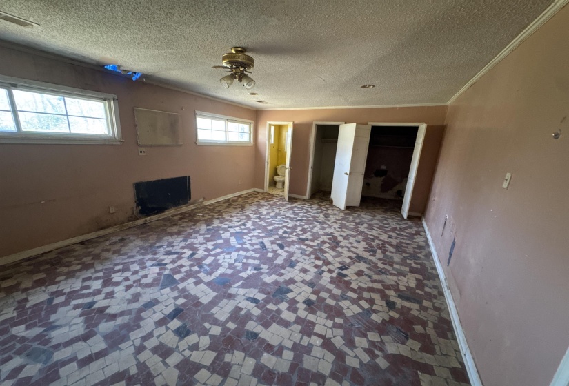 Unfurnished bedroom with two closets, a textured ceiling, and ceiling fan
