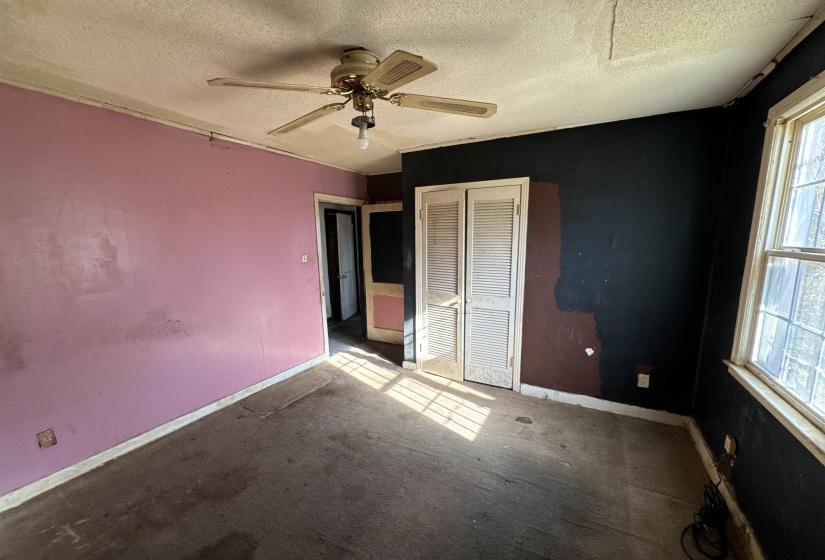 Unfurnished bedroom with a textured ceiling, carpet, ceiling fan, and a closet