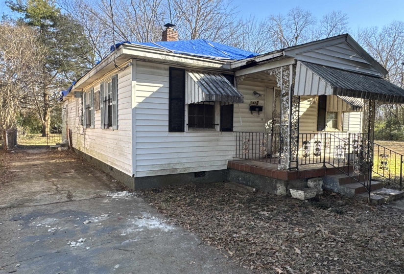 View of front facade with covered porch, crawl space, and a chimney