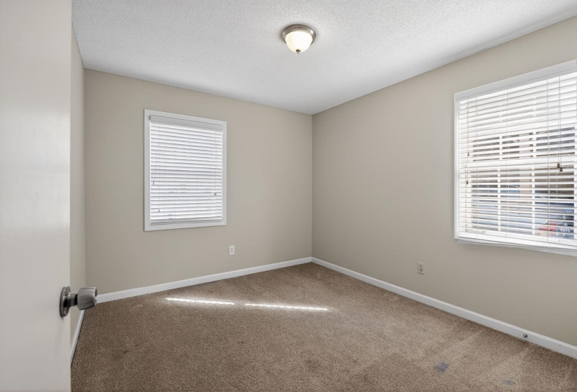 Carpeted empty room with a textured ceiling and healthy amount of natural light