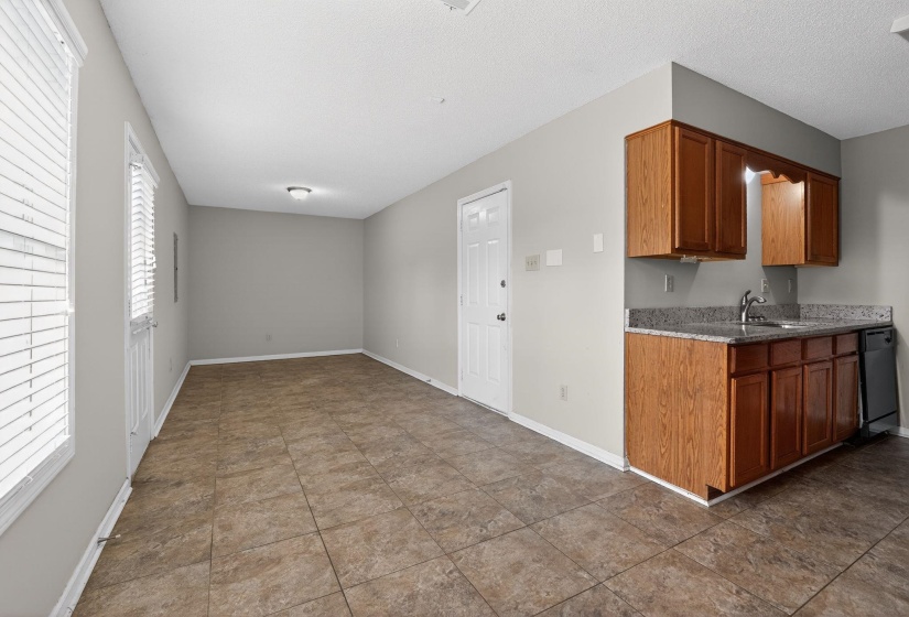 Kitchen featuring brown cabinetry, dishwasher, and light stone counters