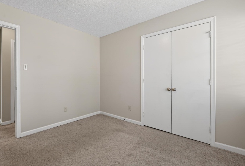 Unfurnished bedroom with light colored carpet, a textured ceiling, and a closet