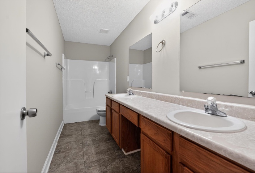 Full bathroom with double vanity, a textured ceiling, and bathtub / shower combination