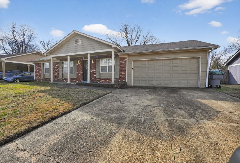 Ranch-style home with a porch, concrete driveway, an attached garage, a front yard, and brick siding