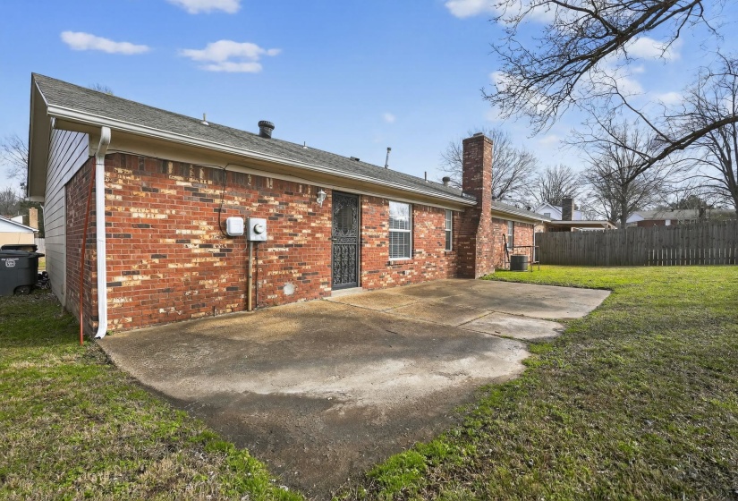 Back of house with brick siding, a patio, a chimney, and roof with shingles