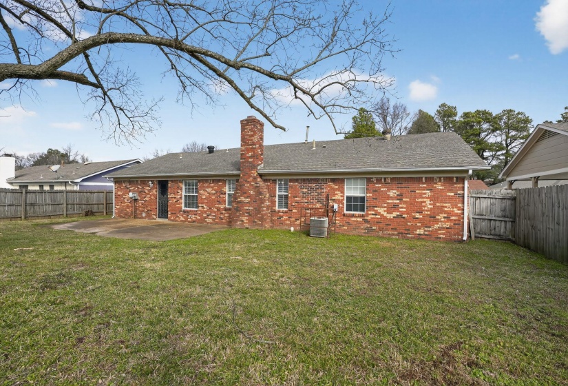 Back of house with brick siding, a fenced backyard, a chimney, a patio, and a shingled roof