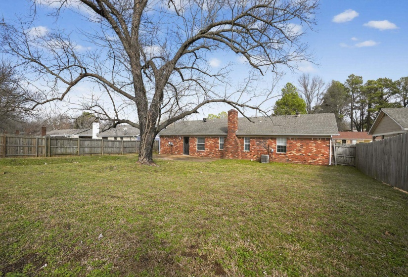 Back of property with a fenced backyard, a chimney, brick siding, and a patio