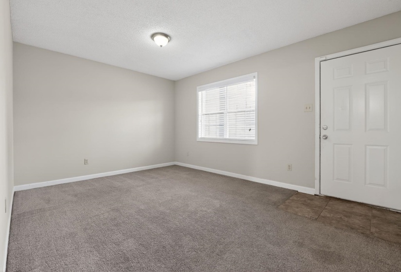 Carpeted foyer entrance featuring a textured ceiling and baseboards
