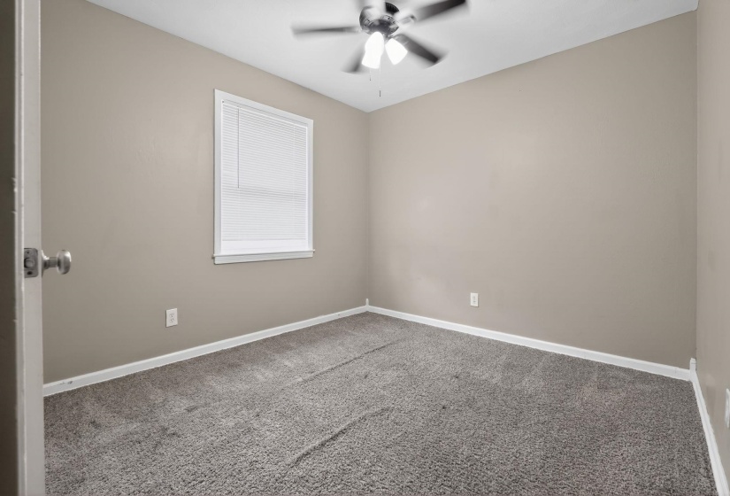 Empty room featuring carpet flooring and a ceiling fan