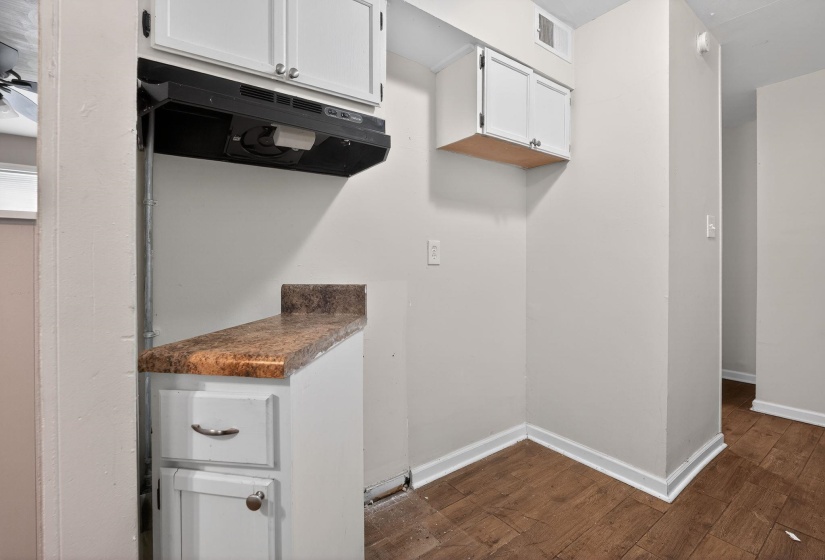 Kitchen with exhaust hood, white cabinets, dark wood finished floors, and dark countertops
