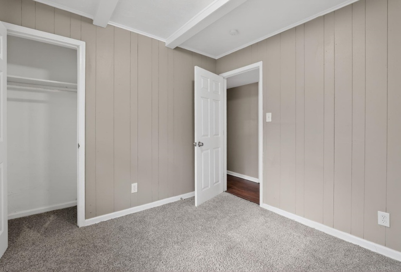 Unfurnished bedroom featuring wood walls, carpet floors, and a closet