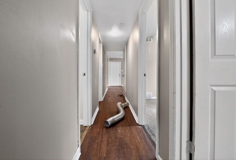 Hall featuring dark wood-style flooring and baseboards