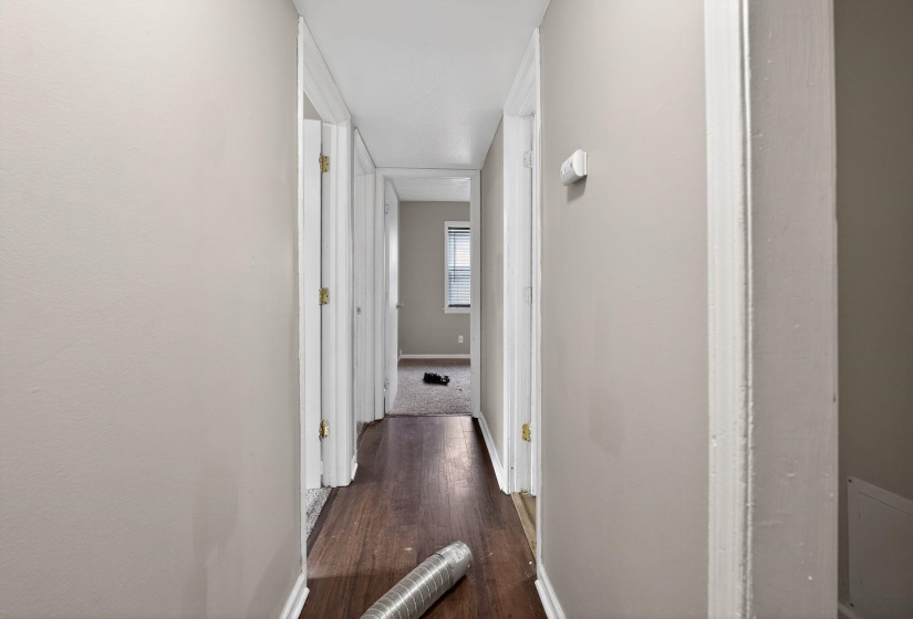 Hall with dark wood-style flooring and baseboards