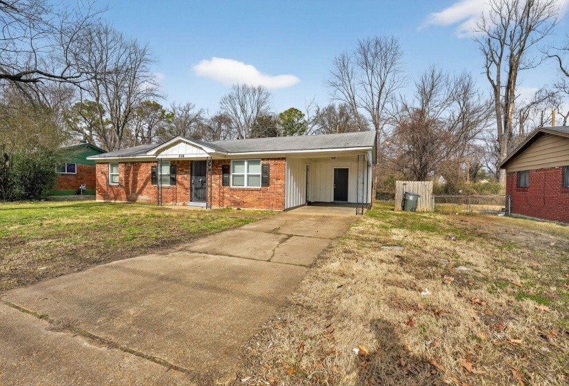 View of front of house featuring an attached carport, driveway, board and batten siding, and brick siding