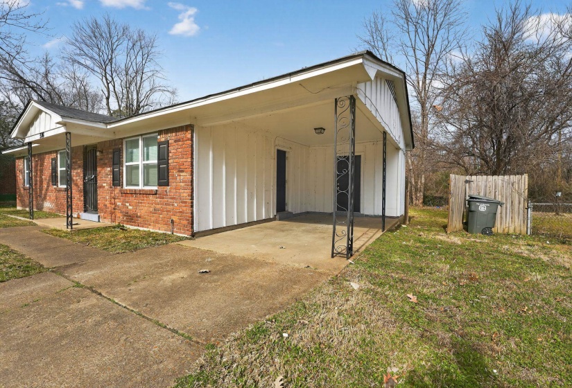 View of home's exterior with a carport, brick siding, concrete driveway, and board and batten siding