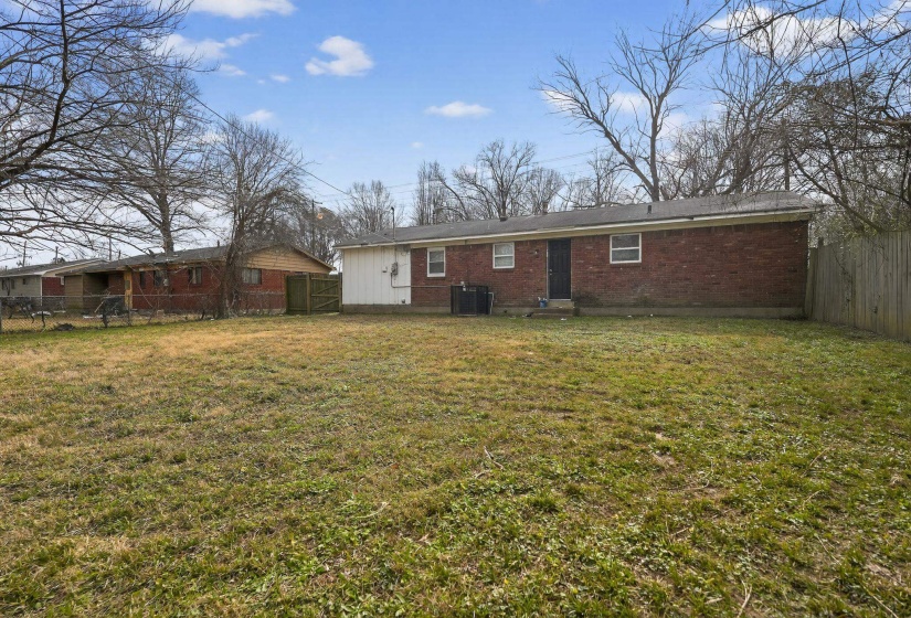 Back of house featuring a fenced backyard, brick siding, and a gate