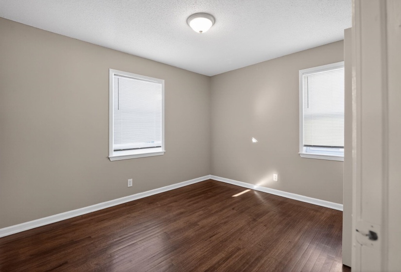 Unfurnished room featuring dark wood-style flooring and a textured ceiling