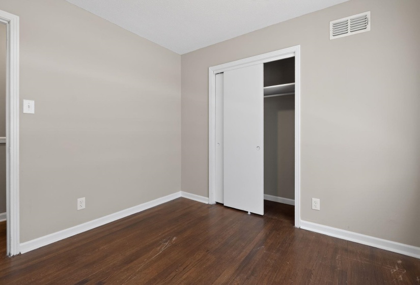 Unfurnished bedroom featuring dark wood-style floors and a closet