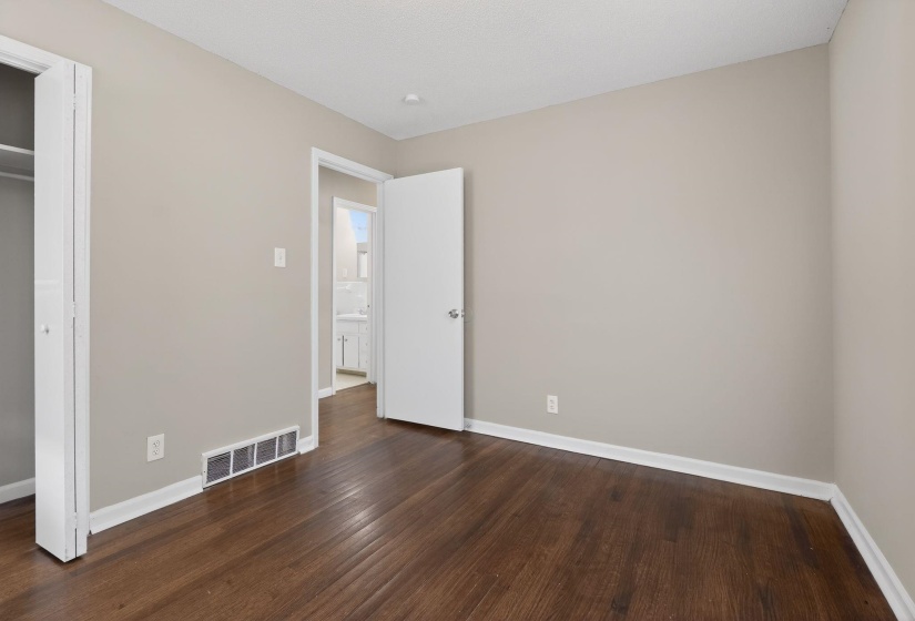 Unfurnished bedroom with dark wood-style floors and a closet