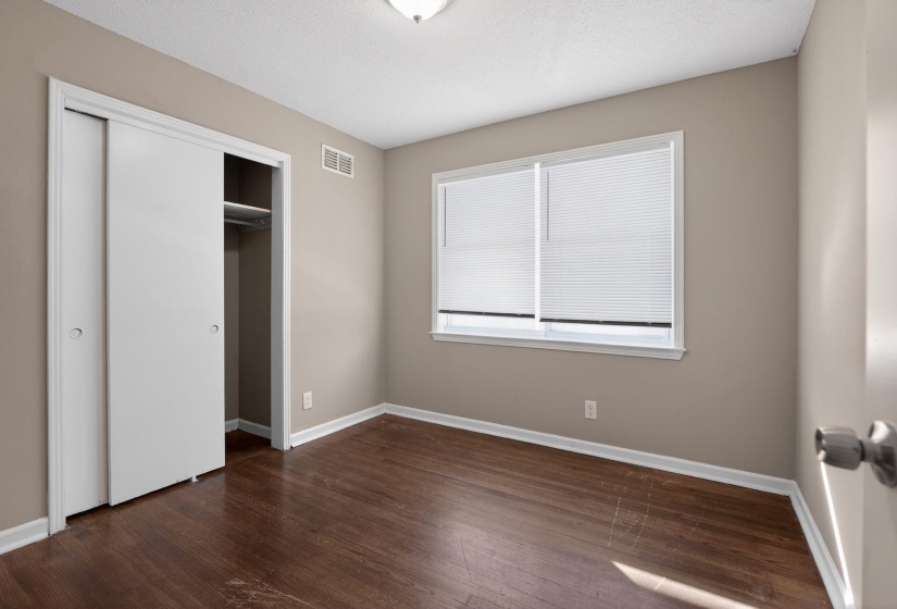 Unfurnished bedroom featuring a closet and dark wood-type flooring