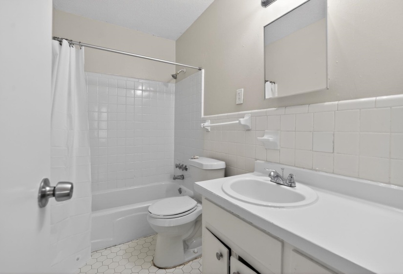 Bathroom featuring tile walls, vanity, shower / bath combo, and a wainscoted wall