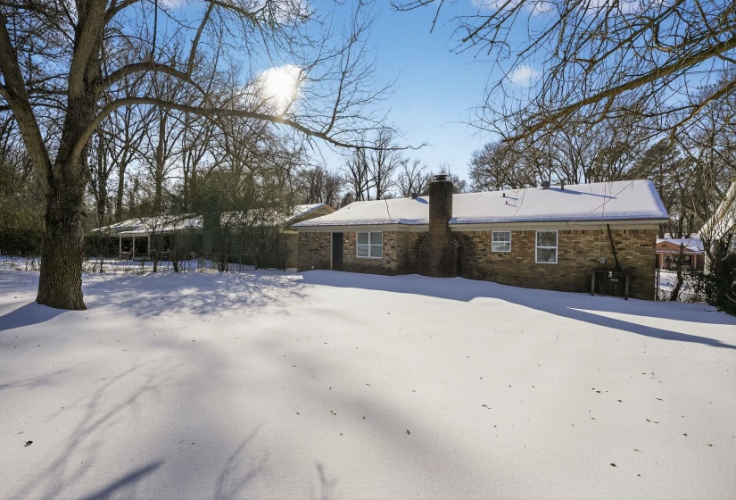Snow covered house with a chimney and brick siding