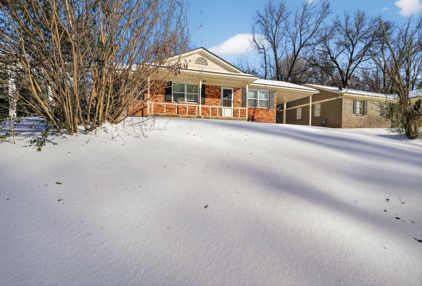 Ranch-style house featuring a carport, brick siding, and a porch