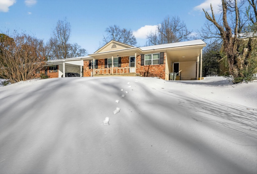 Ranch-style home featuring an attached carport, brick siding, and covered porch