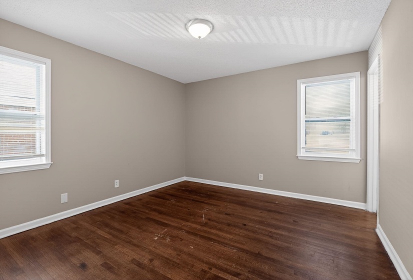 Empty room featuring dark wood-type flooring and plenty of natural light
