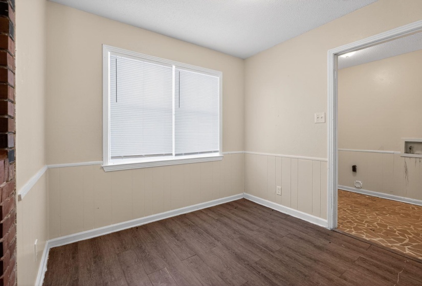 Empty room featuring a wainscoted wall, dark wood-style floors, and a textured ceiling