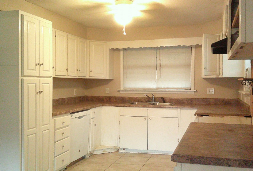 Kitchen with white cabinets, white appliances, dark countertops, exhaust hood, and light tile patterned flooring