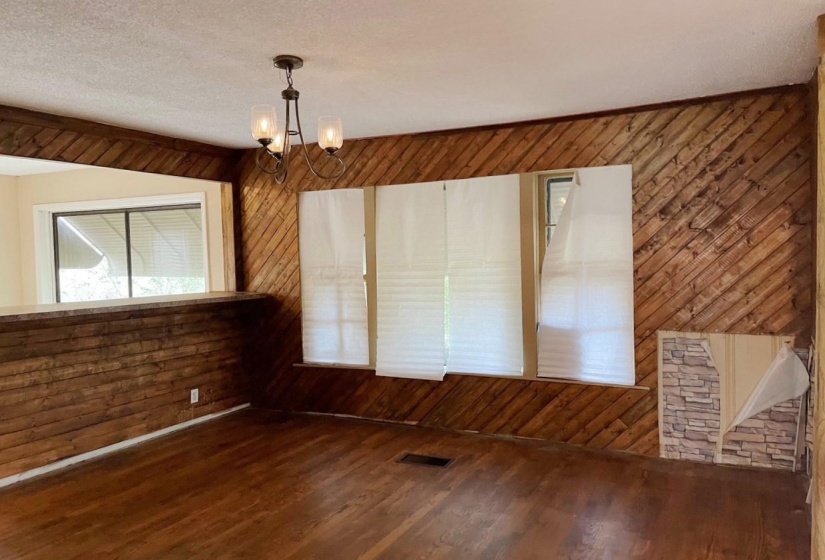 Unfurnished room with wooden walls, a chandelier, wood finished floors, and a textured ceiling