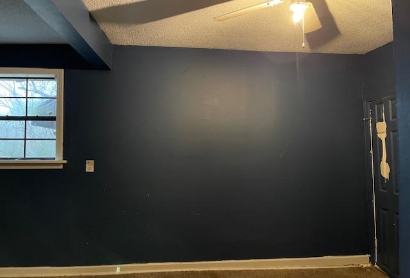 Carpeted empty room featuring a textured ceiling and a ceiling fan