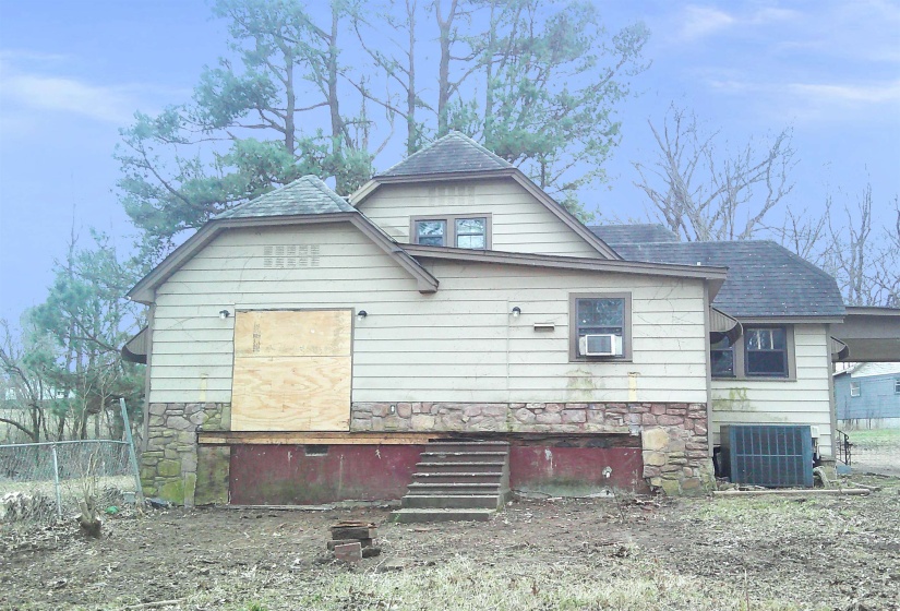 View of side of home with stone siding and a shingled roof