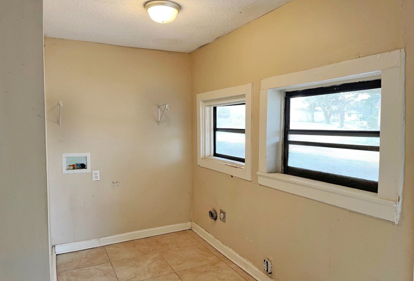 Washroom with hookup for a washing machine, a textured ceiling, and light tile patterned floors