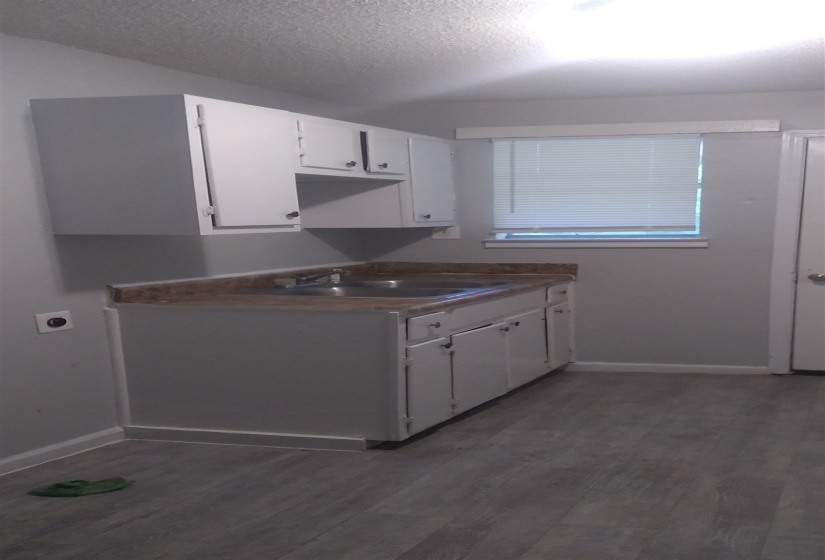 Kitchen with white cabinetry, dark wood-type flooring, a textured ceiling, and dark countertops