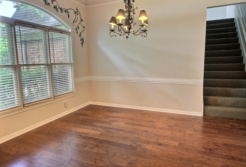 Unfurnished dining area with crown molding, dark wood-type flooring, a chandelier, and stairway