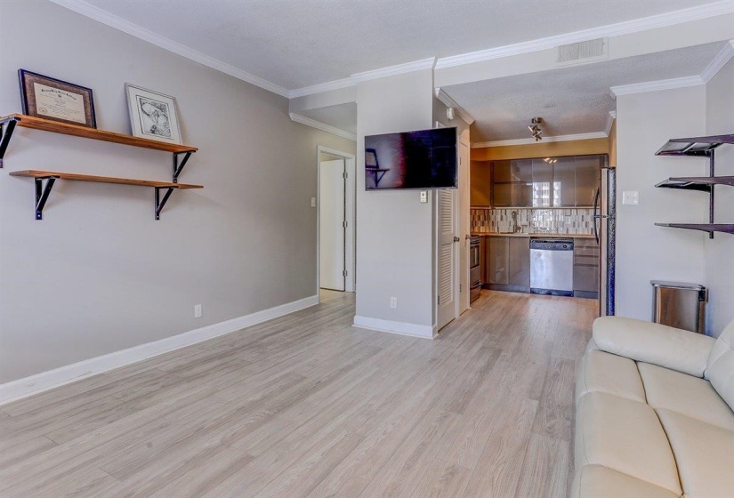 Unfurnished living room with light wood-style flooring and crown molding