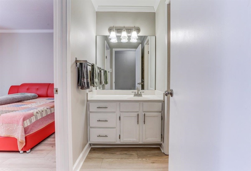 Ensuite bathroom with vanity, ornamental molding, and light wood-type flooring