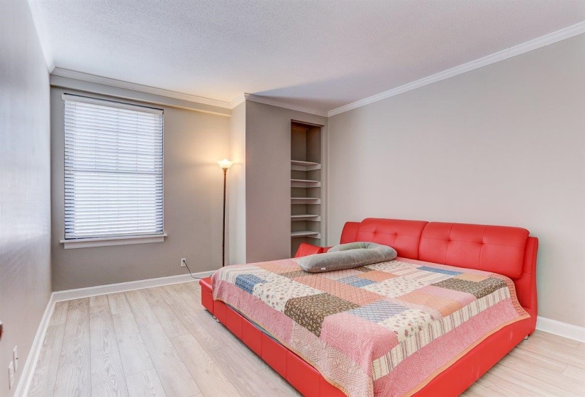 Bedroom with light wood-style flooring, crown molding, and a textured ceiling